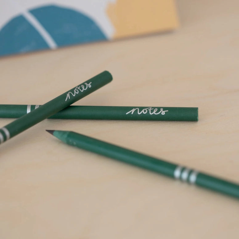 Three green recycled pencils on cream surface