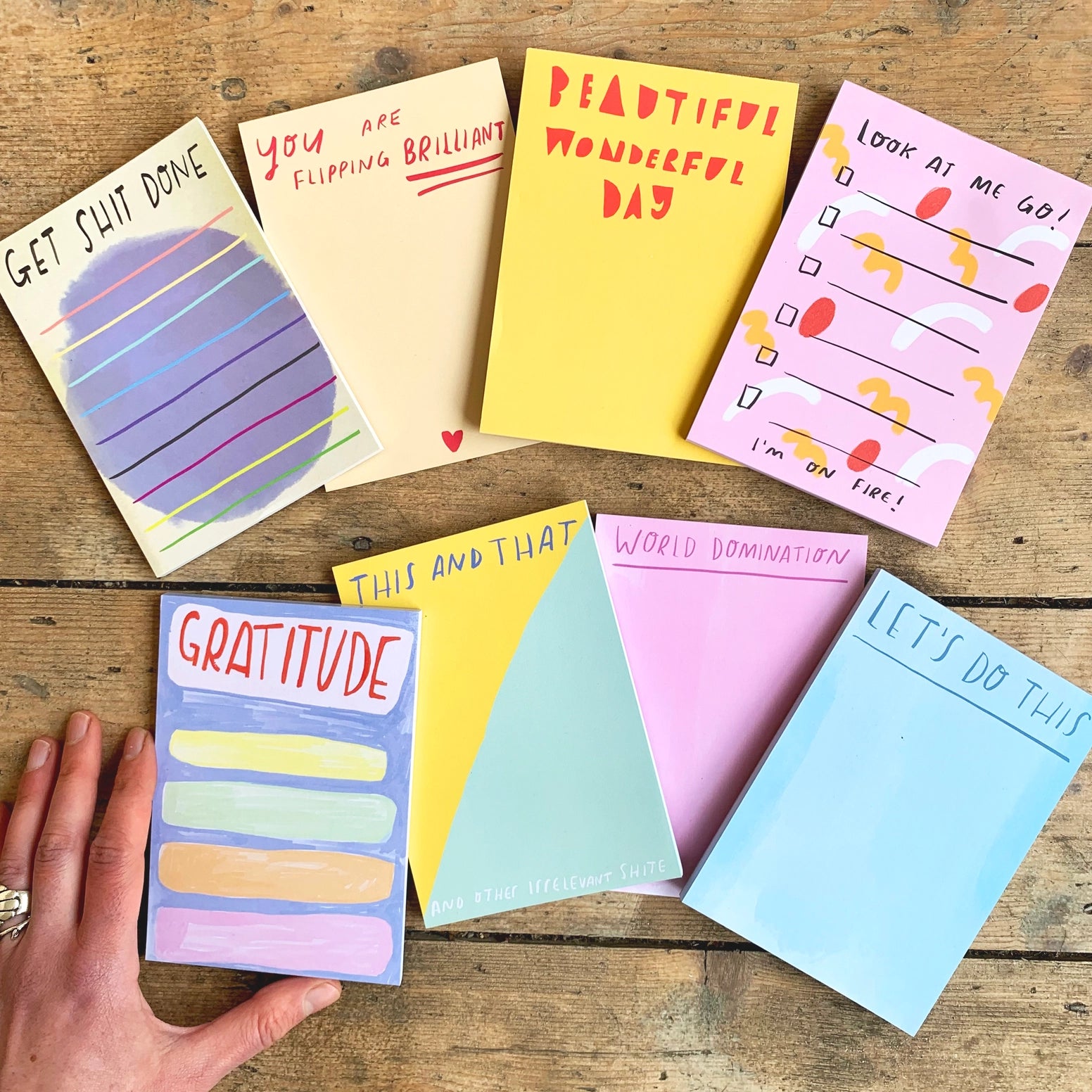 Collection of colorful notepads with various messages on a wooden surface.