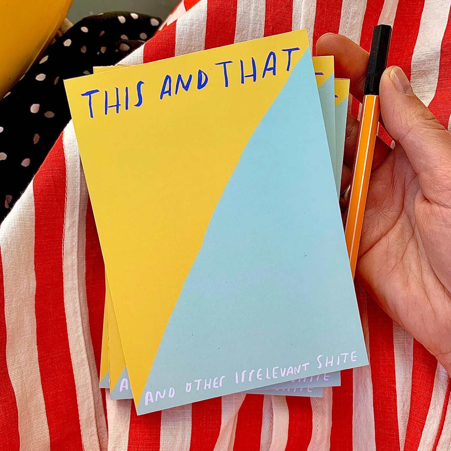 Colorful notepad with text held against a striped fabric background