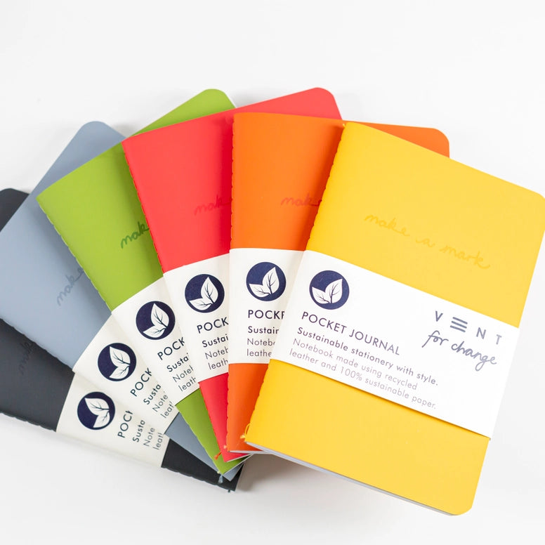 A variety of different coloured recycled leather notebooks fanned out on a white background