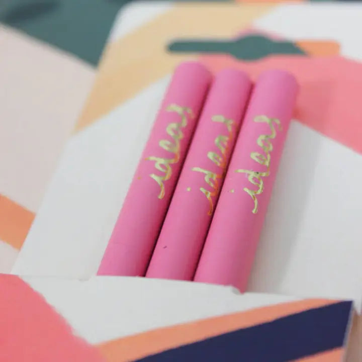 Close up of three dark pink recycled pencils showing the word &