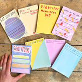Collection of colorful notepads with various messages on a wooden surface.
