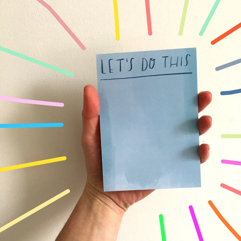 Hand holding a blue notepad with &