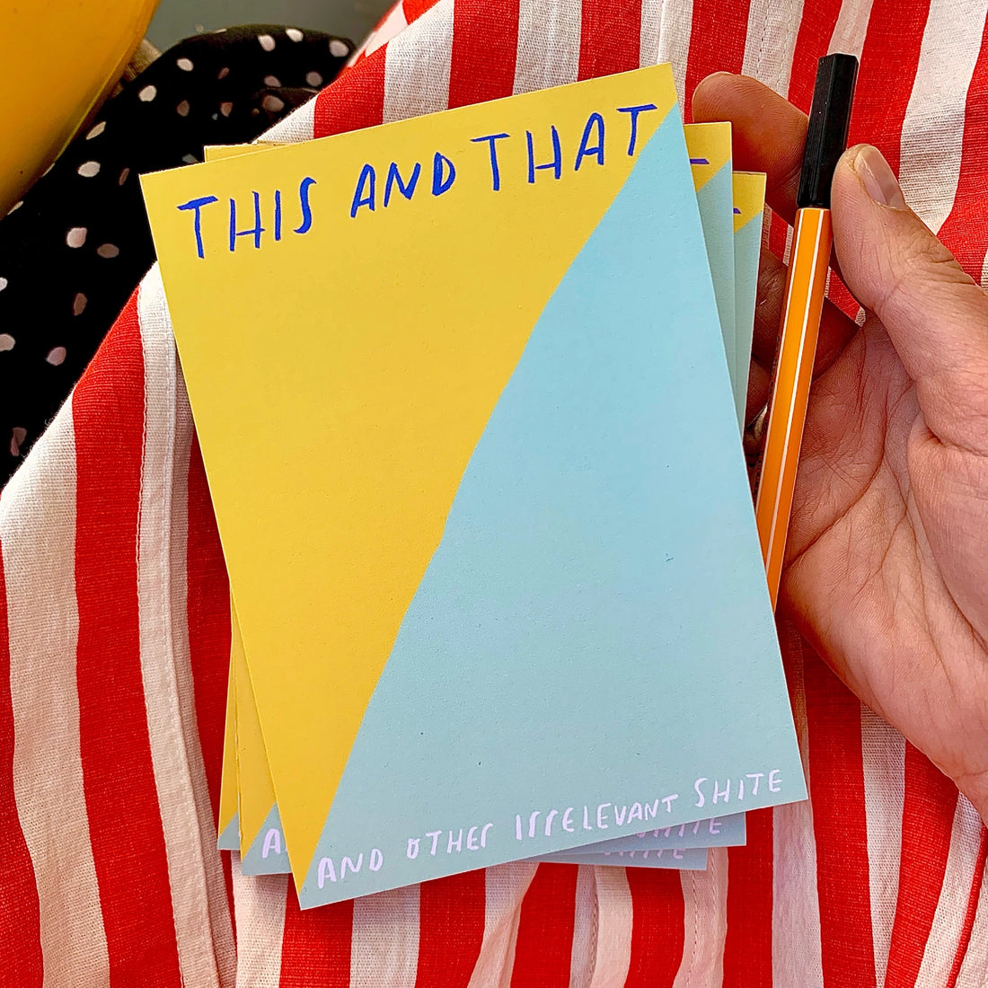 Colorful notepad with text held against a striped fabric background